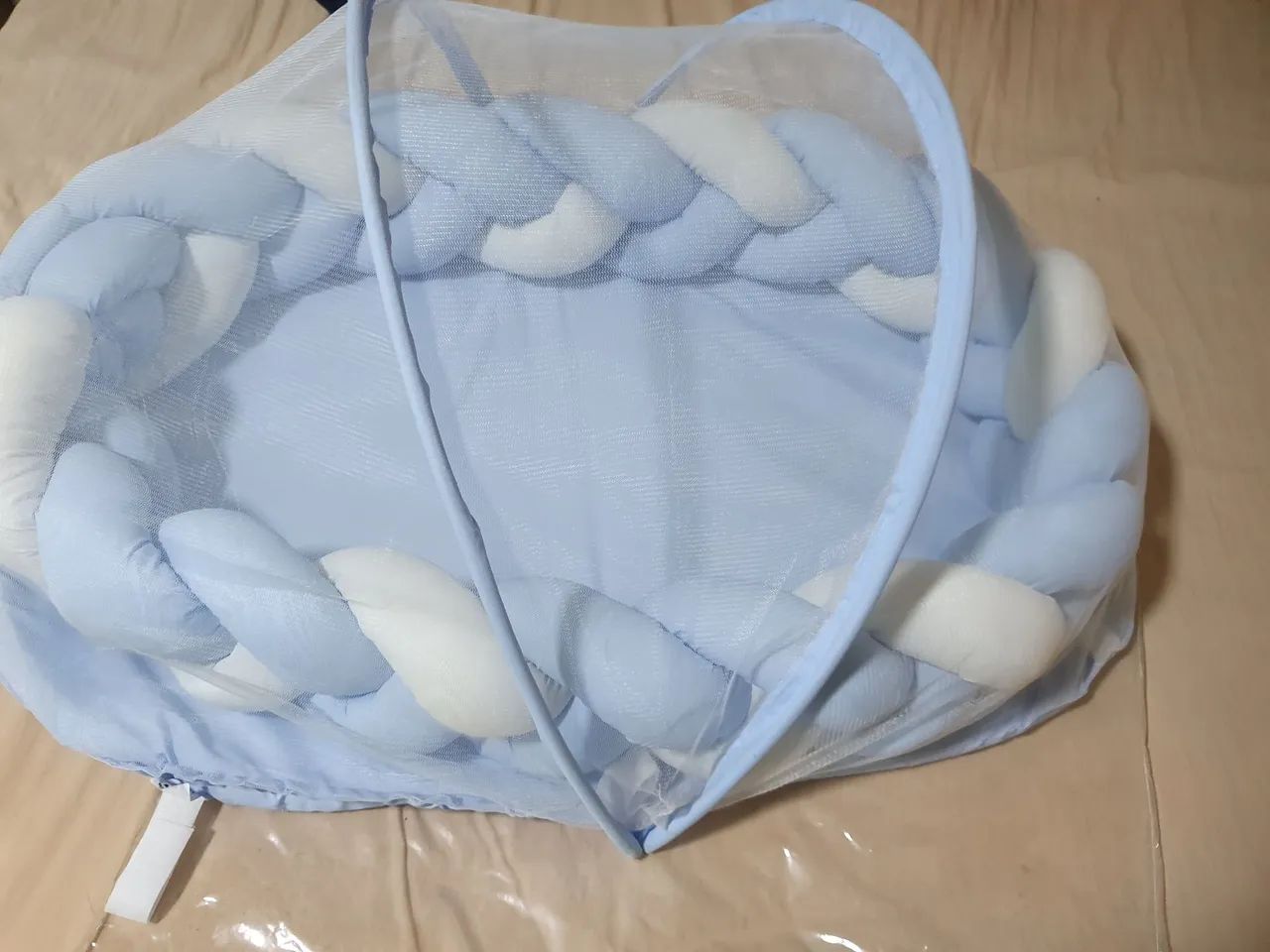 Ninho redutor de berço com trança e mosquiteiro.