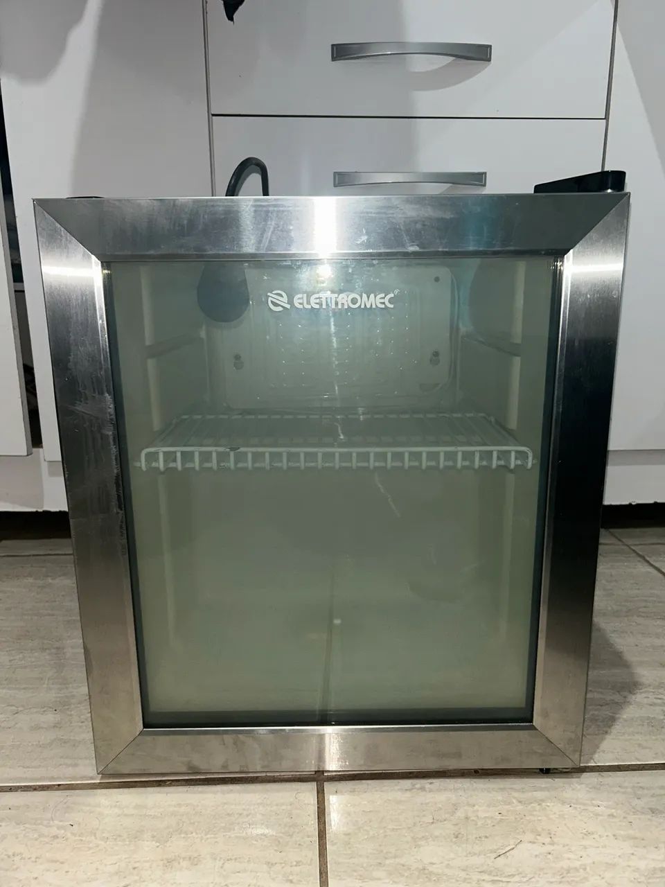 frigobar Elettromec 110V, com acabamento inox e porta de vidro.