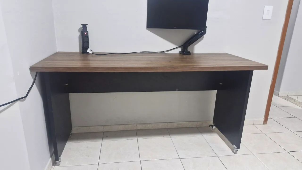 Escrivaninha com suporte monitor articulado e torre de tomada e cadeira.