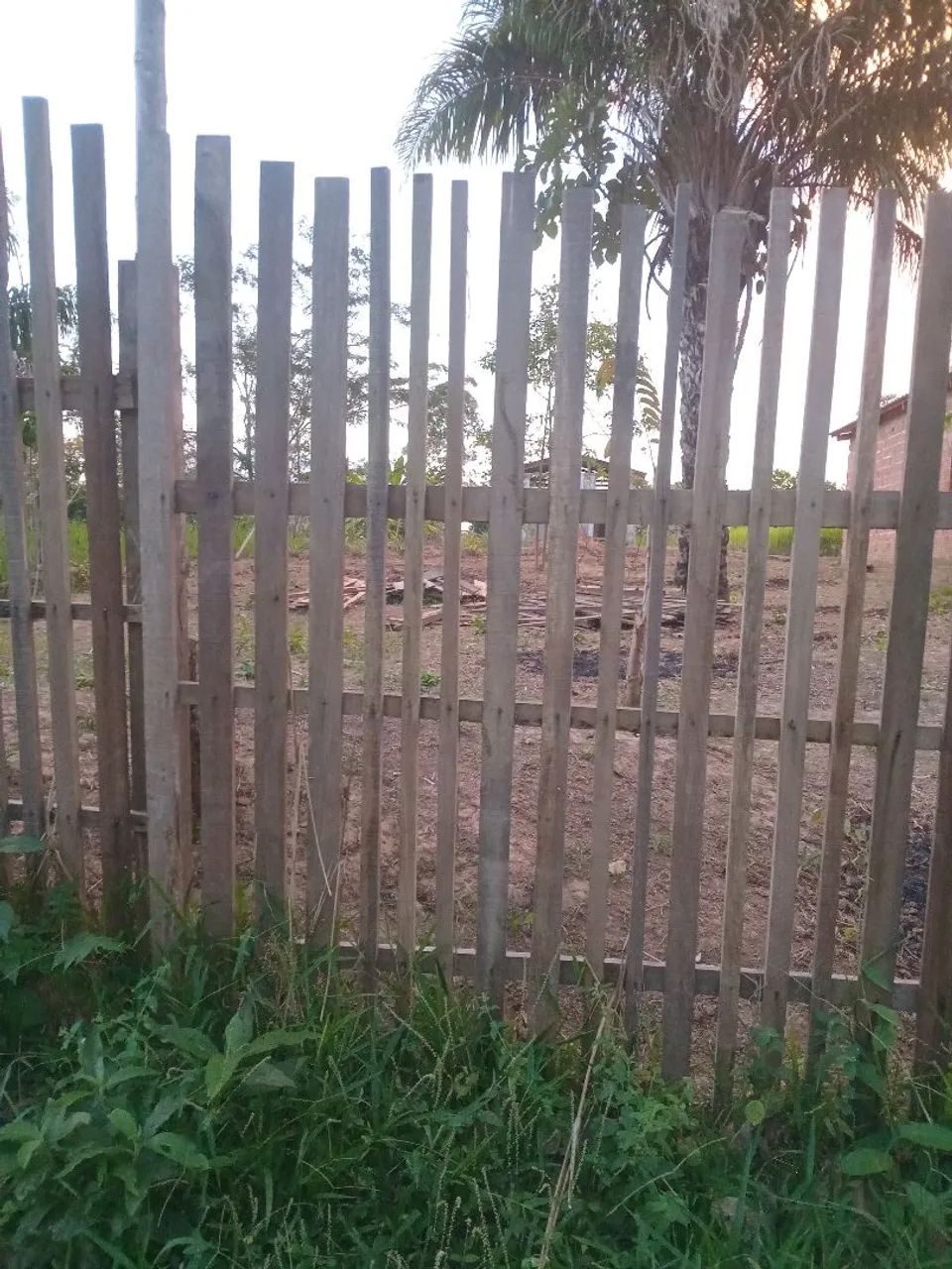 Terreno com casa de madeira inacabada. 