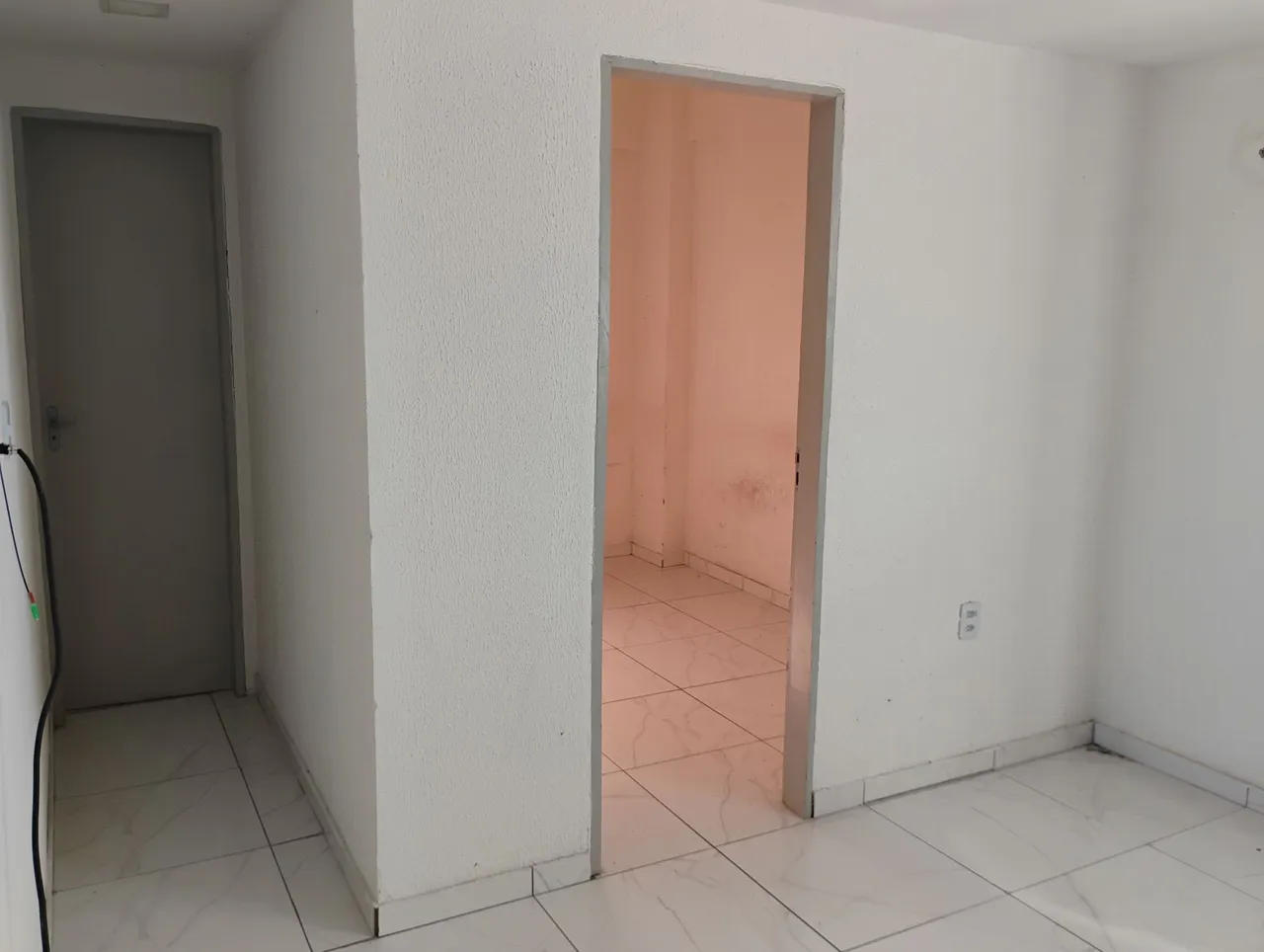 Cômodo com piso branco e porta cinza