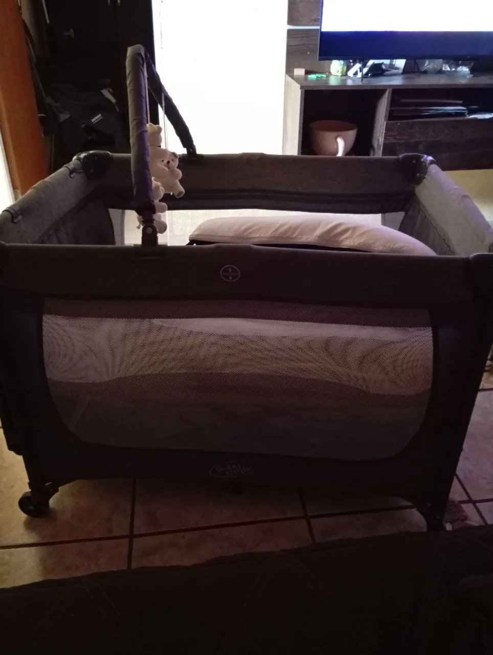 Berço portátil cinza com móbile