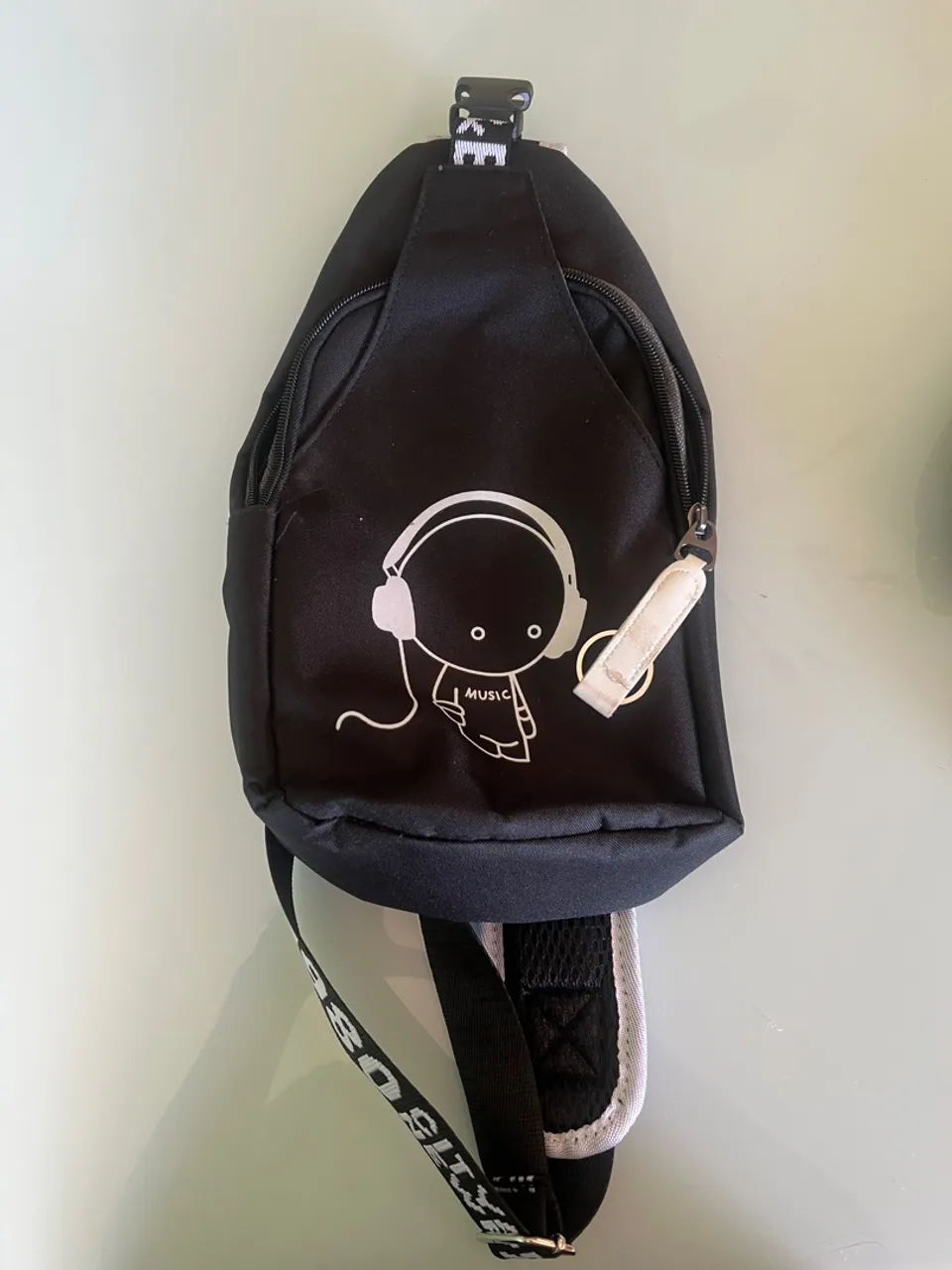 Mochila transversal preta com design musical
