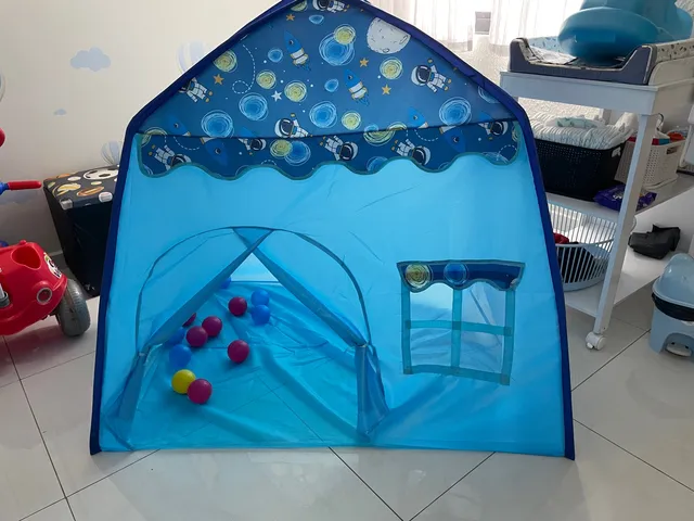 Quarto de criança com tenda e jogo de brincar com ursinho no chão.