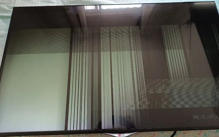 TV LG de 49 polegadas com imagem distorcida e linhas verticais na tela.