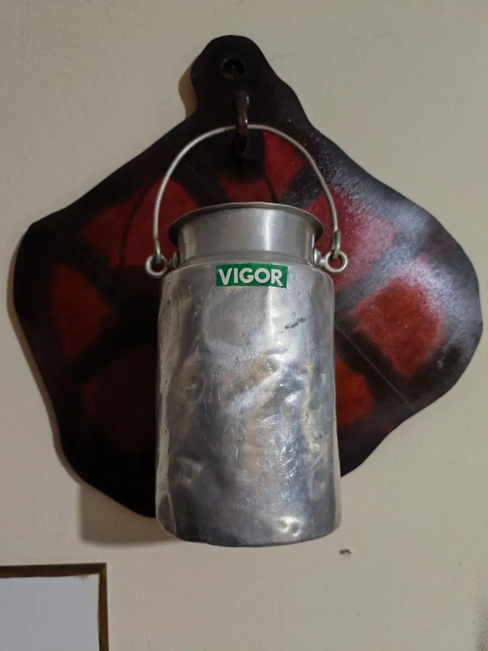 Leiteira antiga em alumínio em placa decorativa.