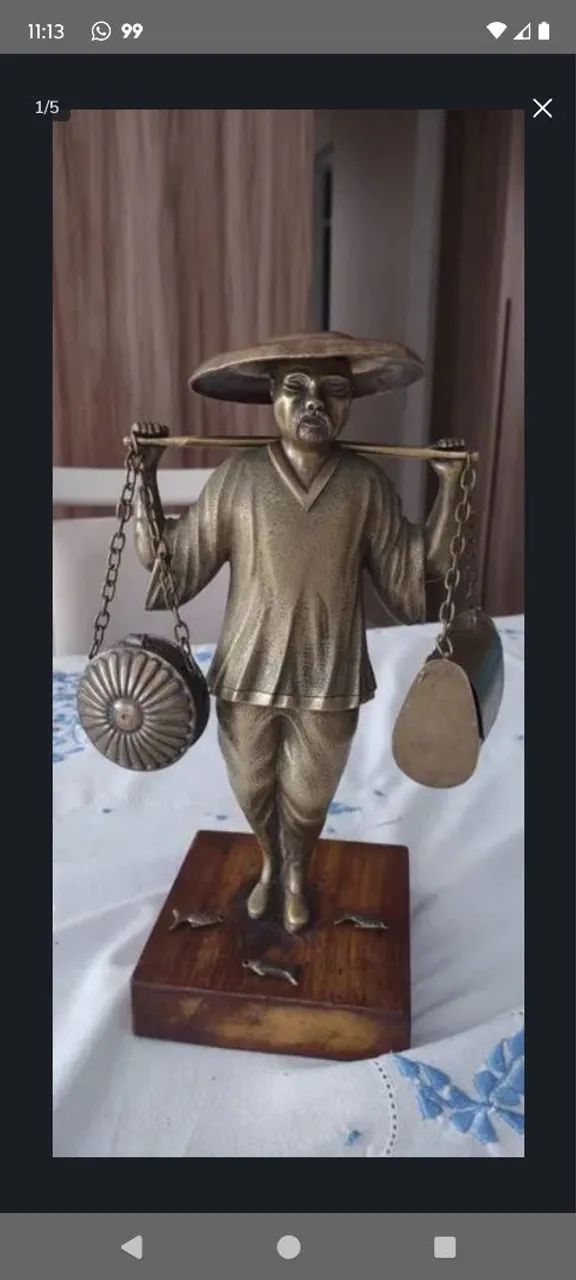 Escultura em bronze de pescador oriental, com alguns peixes na bolsa