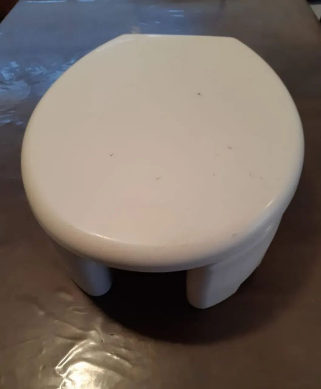 Assento sanitário elevado com tampa, modelo oval na cor branca.