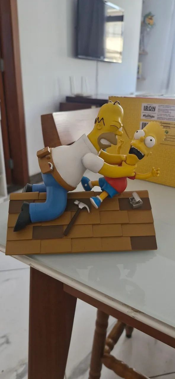 Estatua do Homer vs Bart no telhado da linha Iron Studios