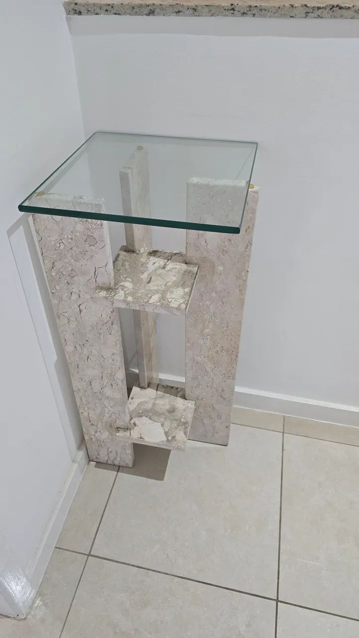 Mesinha com base em pedra e tampo em vidro.