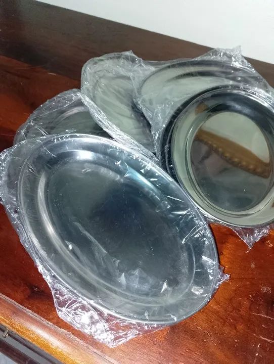 12  travessas de inox  novas , sem uso , tamanho médio.