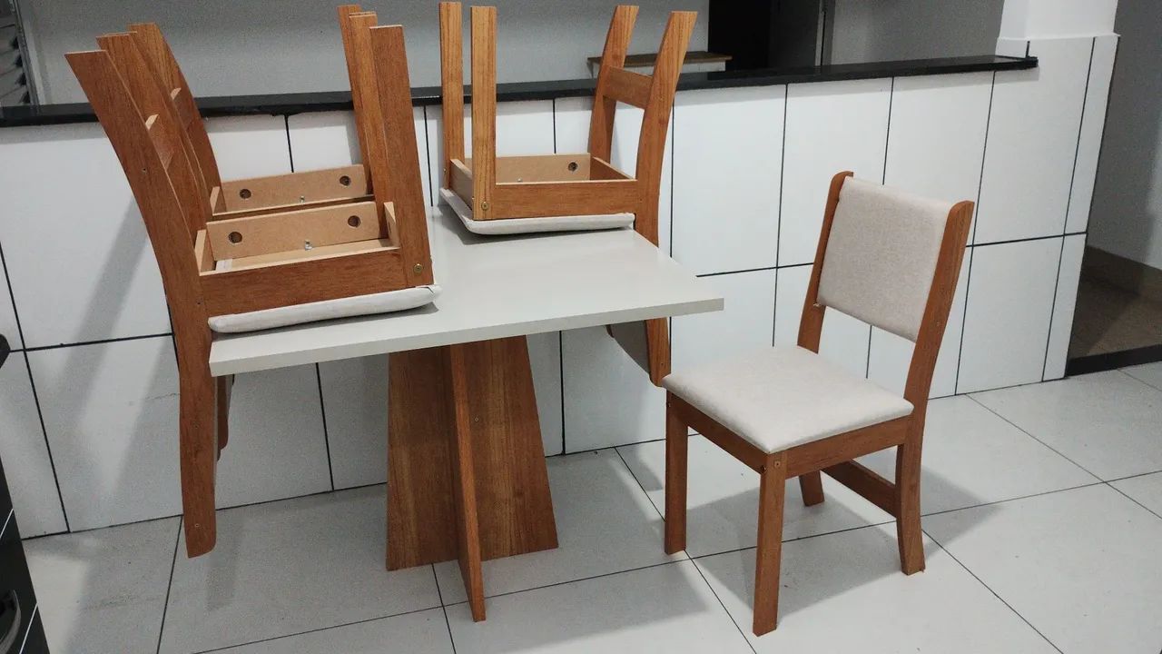 Mesa com quatro cadeiras estofadas. 