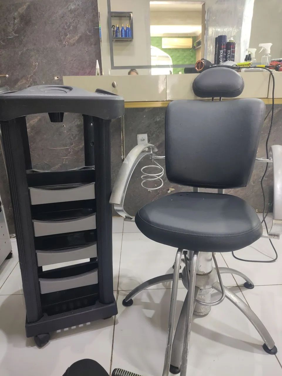 Um cadeira para cabeleireira e um carrinho auxilia