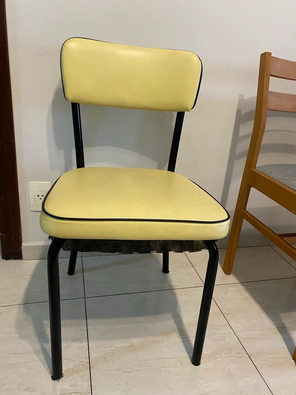 Cadeira estofada em amarelo, acabamento em preto e base metal.