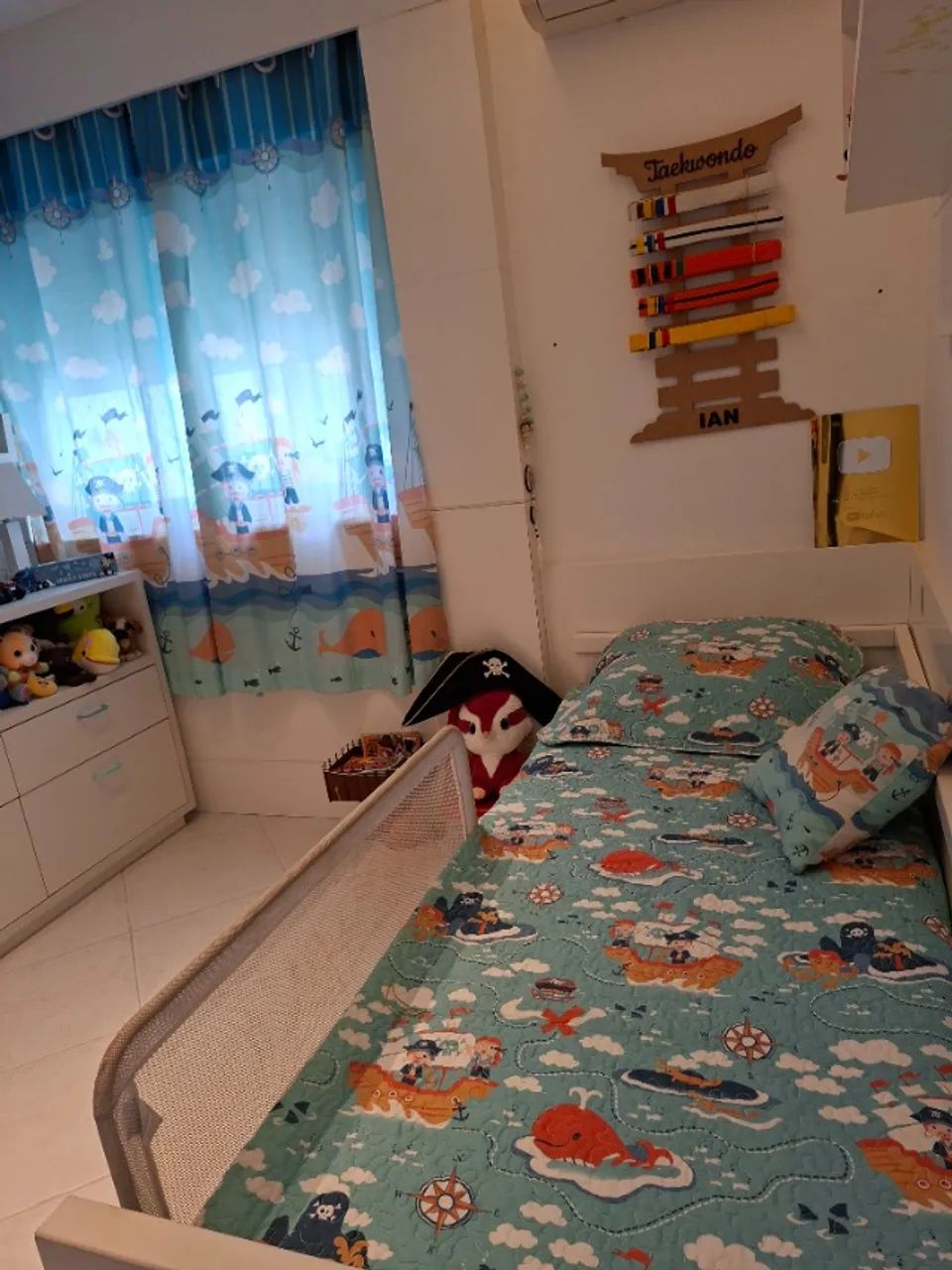 Colcha, almofada e cortina decorativas para quarto de criança.