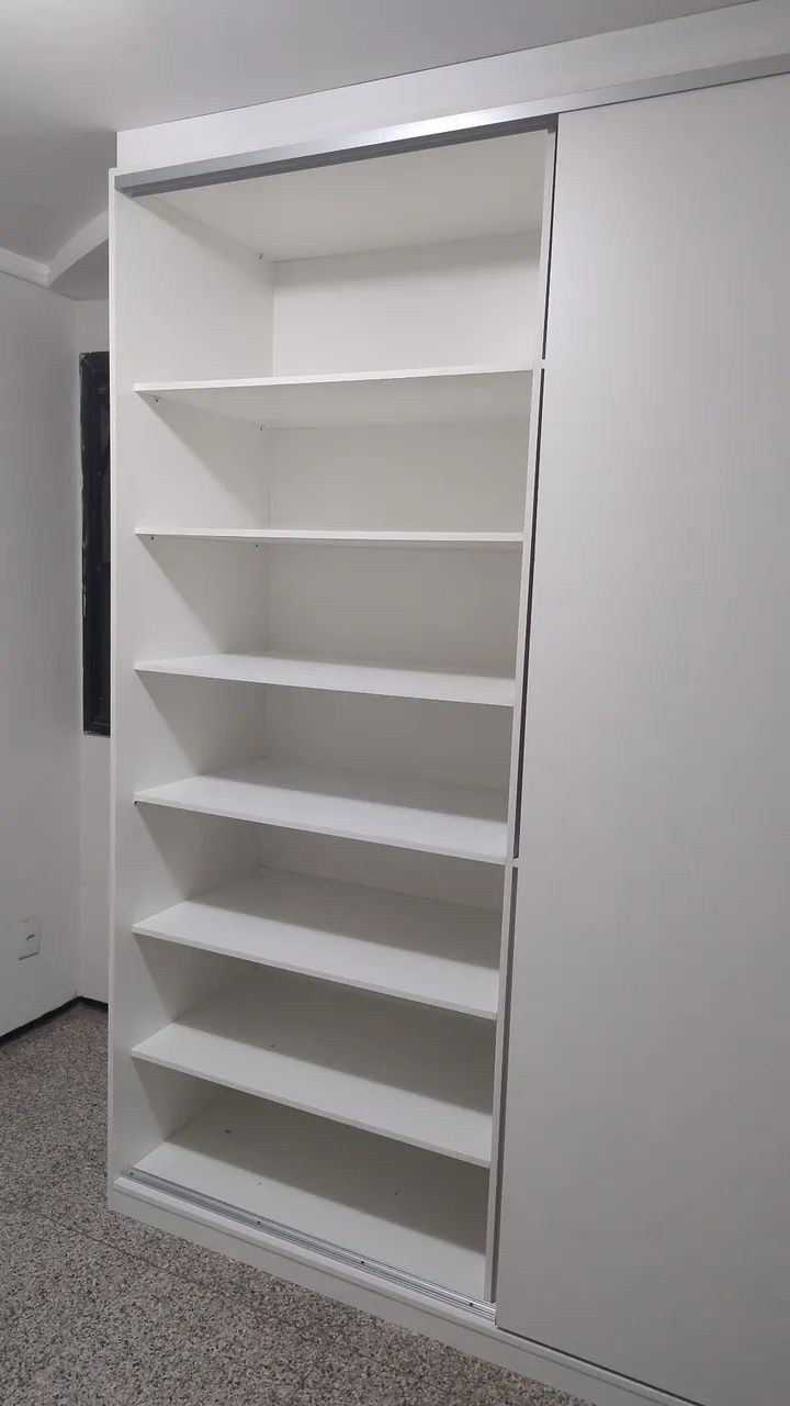 Armário de portas de correr branco com prateleiras e gavetas.