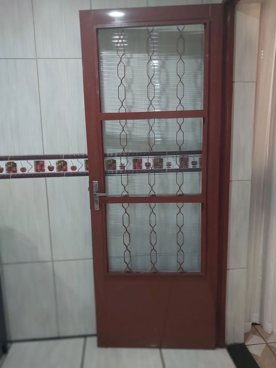 Porta de ferro com vidro e grade com uma chave sem batente