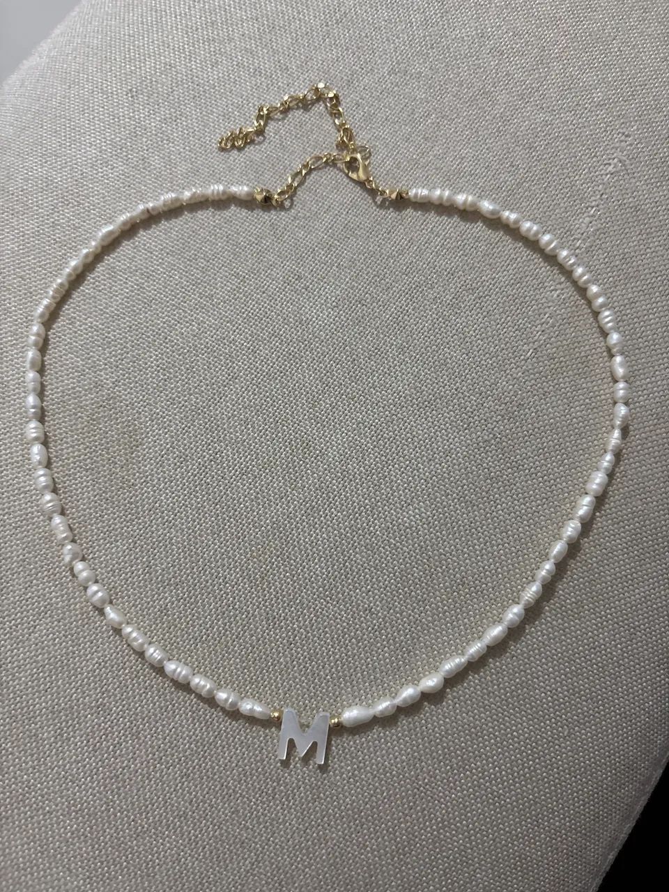 Colar de pérola com letra M.