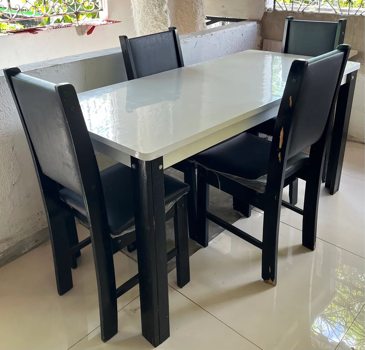 Conjunto de mesa com 4 cadeiras em fórmica branca.