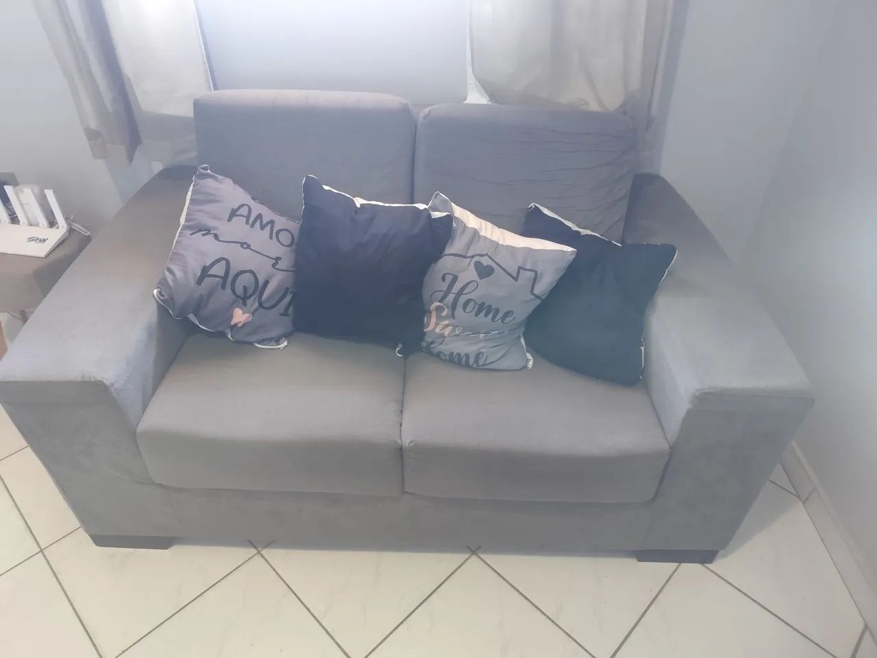 Sofa 2 lugares cinza escuro e almofadas.