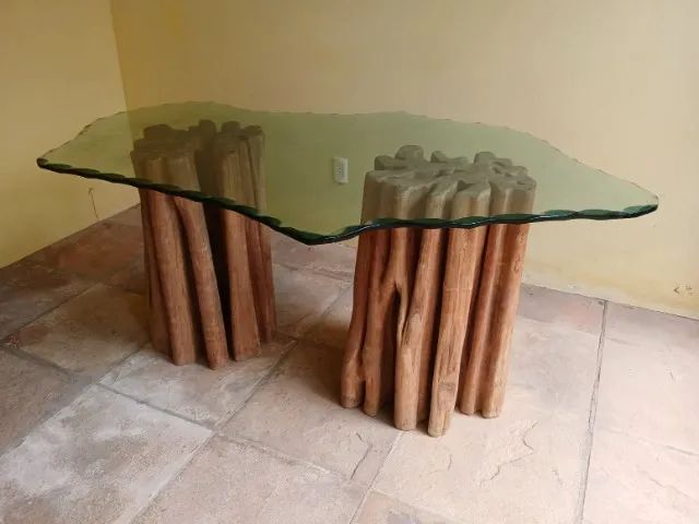 Mesa de jantar com bases em tronco de guarantã e tampo de vidro