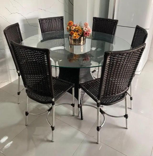 Conjunto de mesa com vidro e cadeiras em fibra sintética.