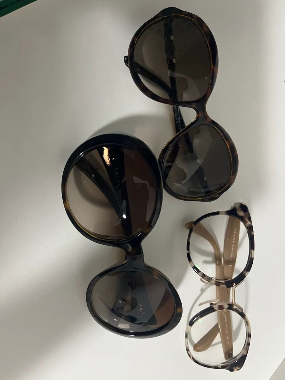 3 óculos sendo 2 de sol Gucci e Prada e uma armação de grau Prada
