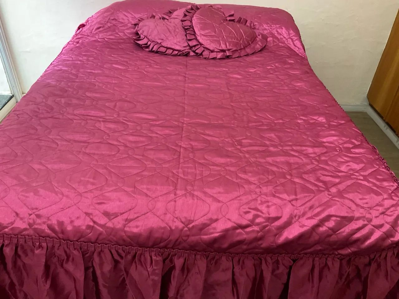 Cobre-leito rosa com almofadas de coração