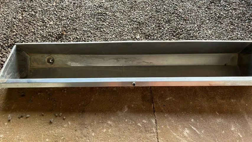 Stainless steel wall-mounted urinal.
