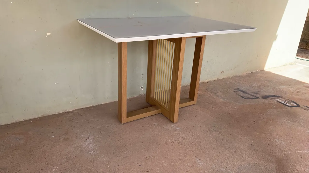 Mesa de jantar com estrutura em madeira com tampa de vidro.