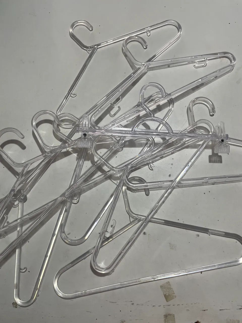 Cabides acrílico transparente, plástico preto, metal, presilha.