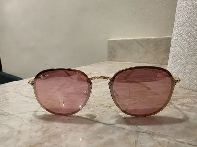 óculos de sol redondo com lentes cor rosa e armação hastes douradas