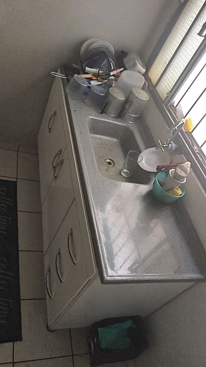 Pia com gabinete e diversos utensílios de cozinha usados