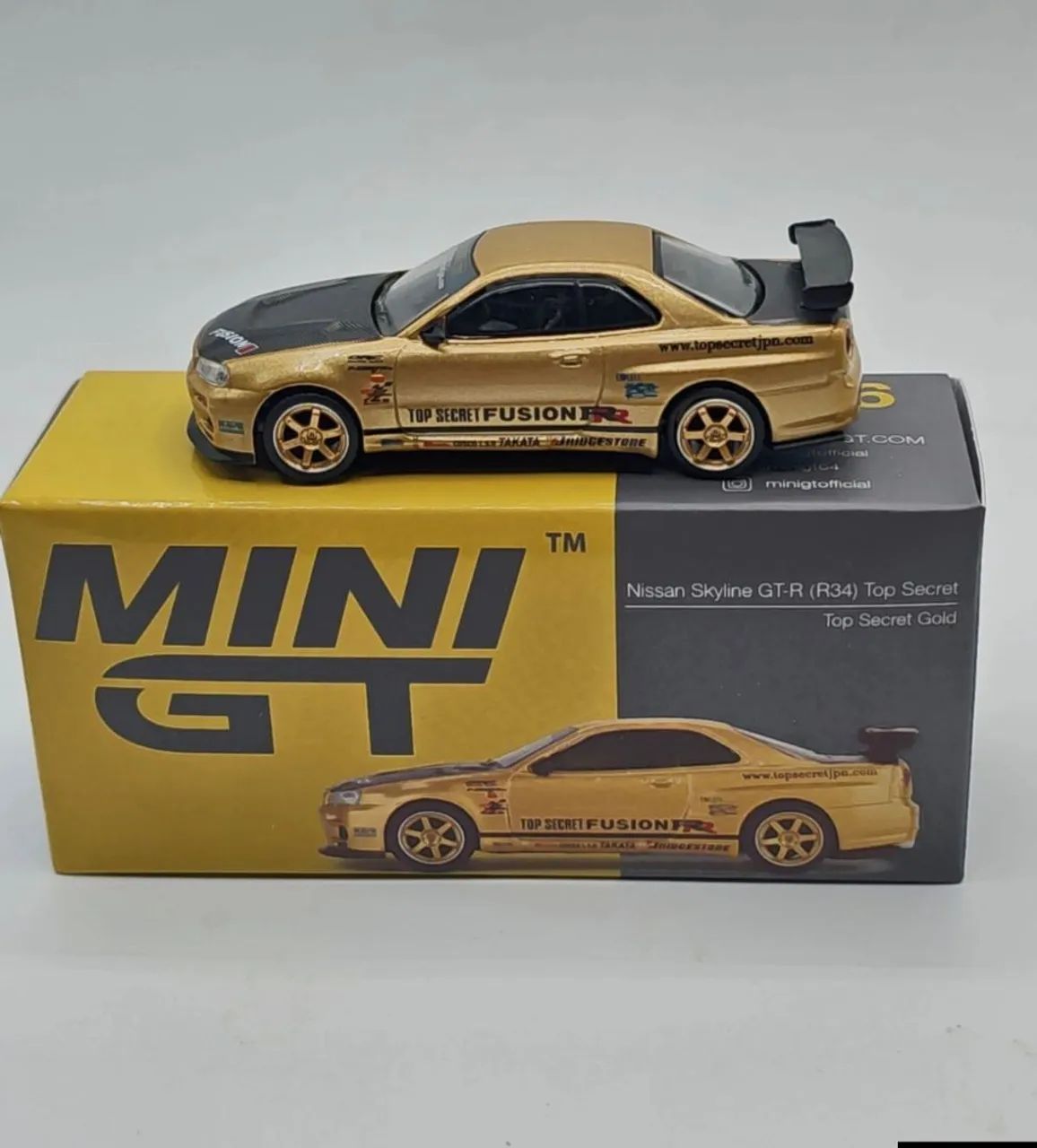 Mini GT Nissan Skyline GT-R (R34) Top Secret Gold Exclusivo do