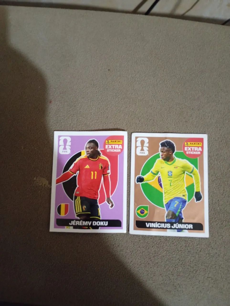 Jérémy Doku Bordo e Vinícius Júnior Bronze Extra Stickers Copa do Mundo 2026