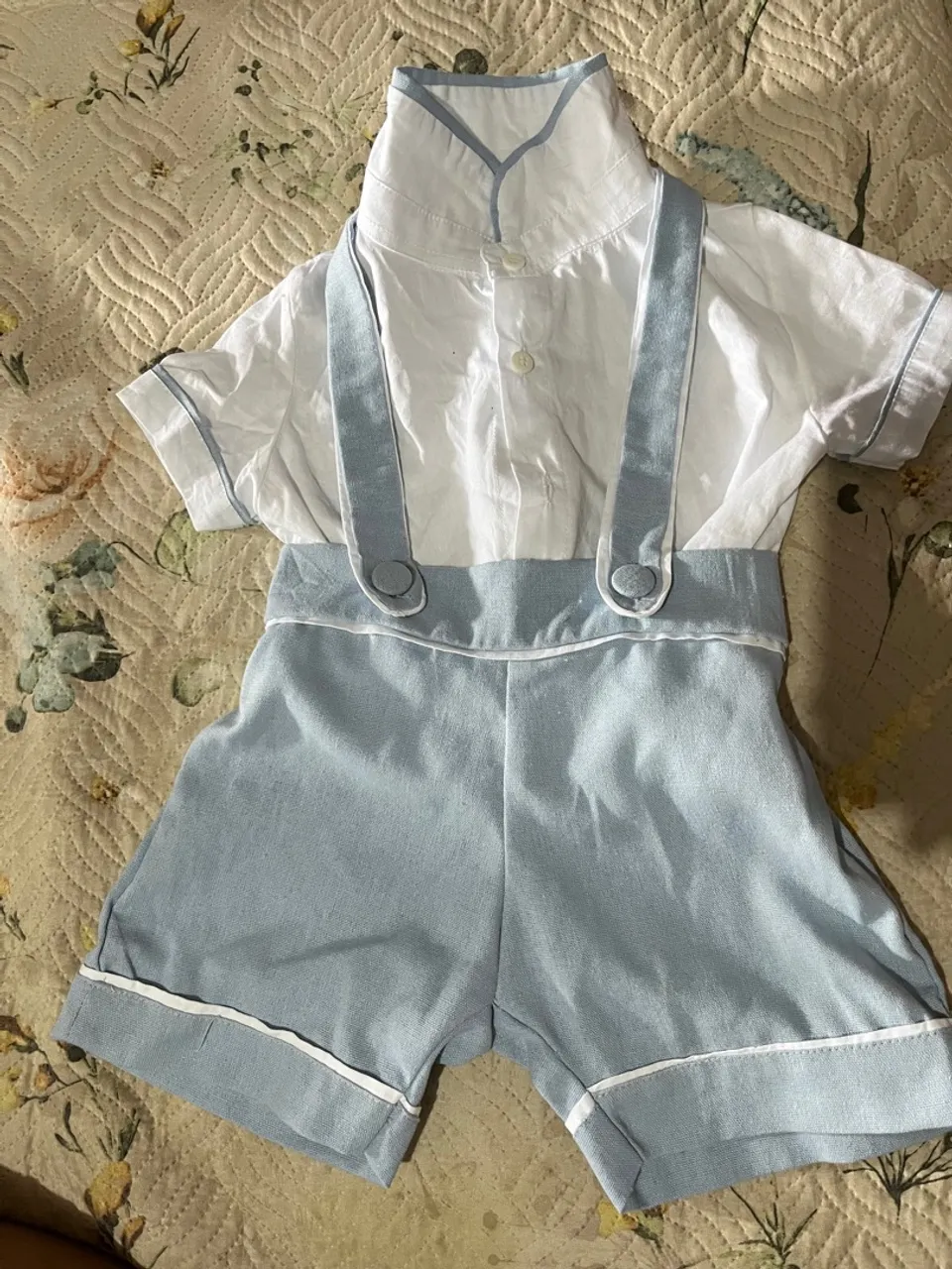 Conjunto de bebê com suspensório azul claro.