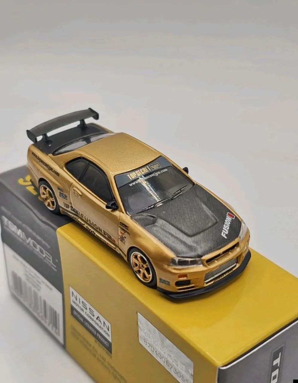 Mini GT Nissan Skyline GT-R (R34) Top Secret Gold Exclusivo do