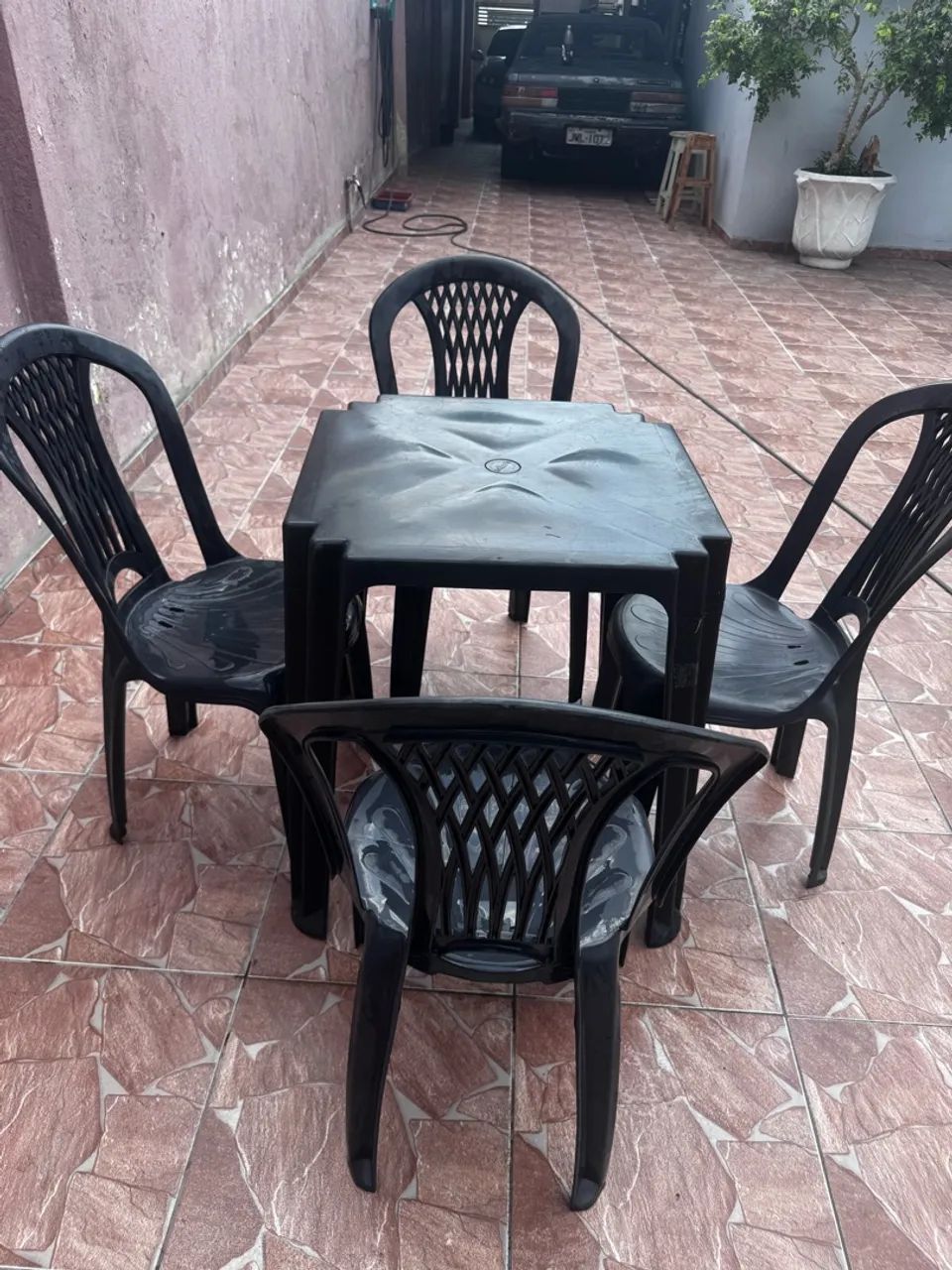 Jogo de mesa com quatro cadeiras de plásticos na cor pretas