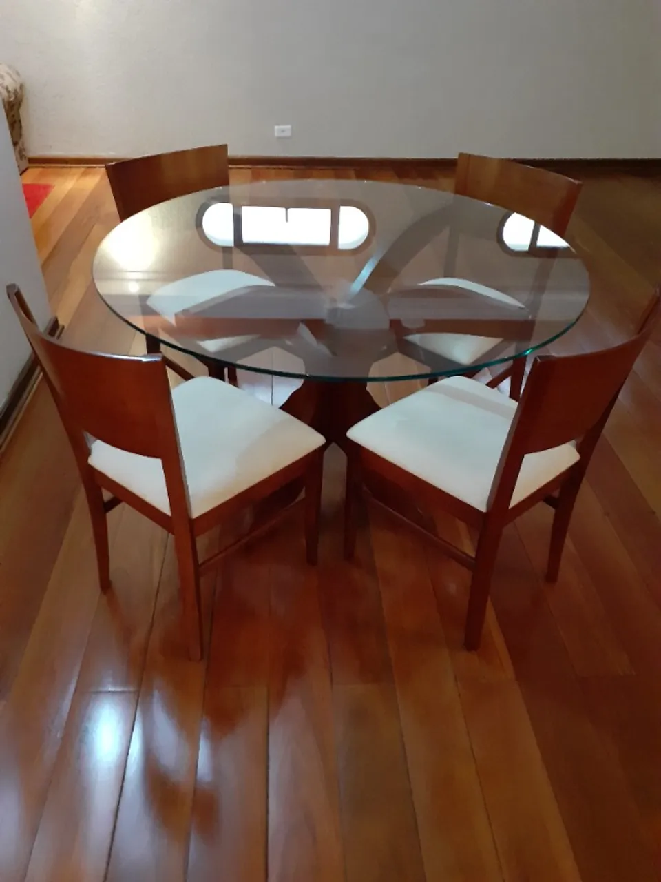 Conjunto de mesa de jantar redonda com quatro cadeiras. Base de madeira e tampo de vidro