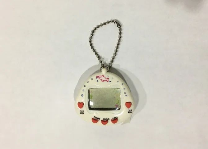 Bichinho Virtual RakuRaku Dinokun TK-910 Branco (Tamagotchi) Anos