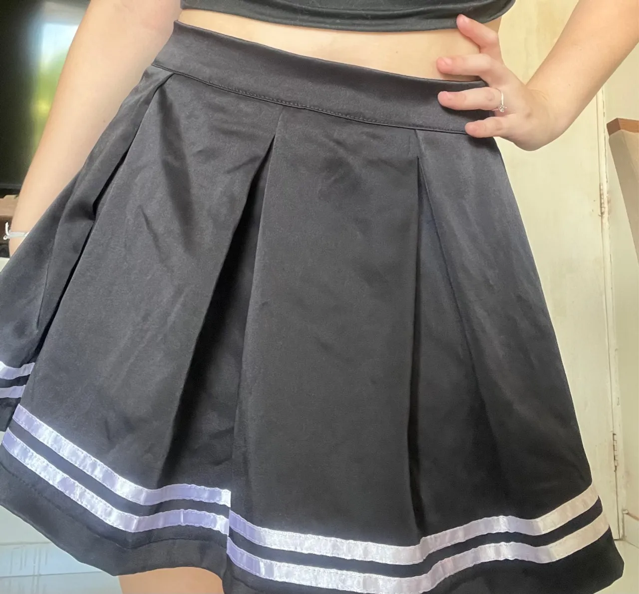 Saia short preta plissada com detalhes em listras brancas