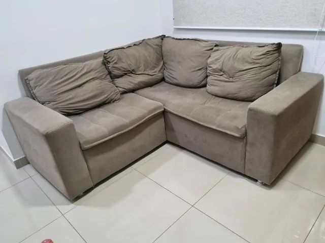 Sofá de canto em tecido com almofadas soltas.
