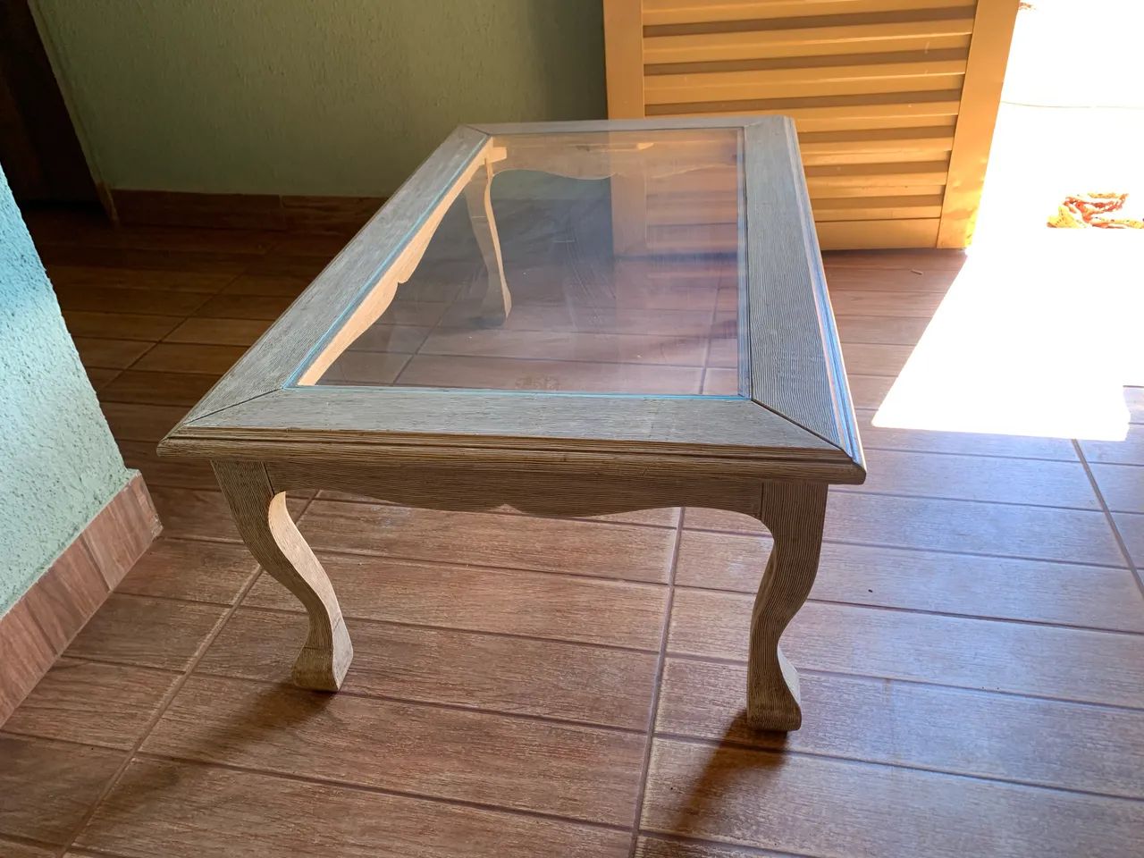 Esta é uma mesa de centro clássica de madeira com tampo de vidro e pés curvados. - Foto 3