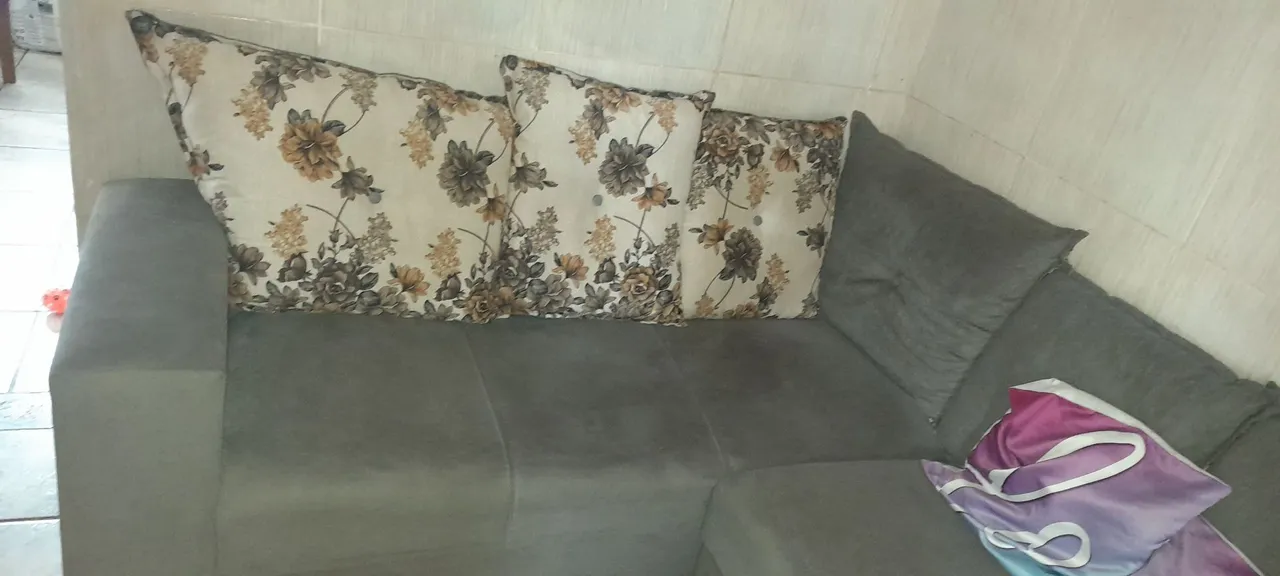 Sofá de canto cinza com almofadas florais