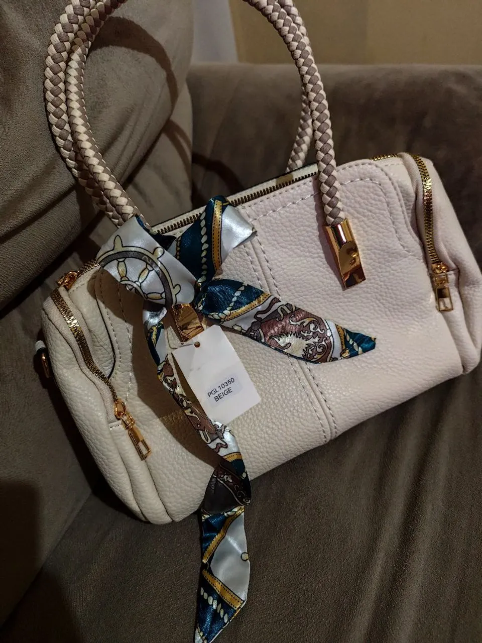 Bolsa de mão bege com alça trançada e lenço decorativo