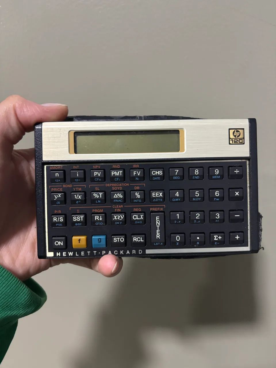  Calculadora Financeira HP 12C clássica com visor LCD e placa frontal dourada.