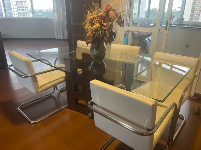 Mesa de Jantar de vidro, base em madeira, cadeiras brancas em aço cromado