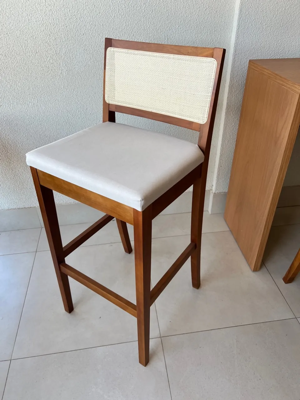 Banqueta de madeira com assento estofado e encosto em palha