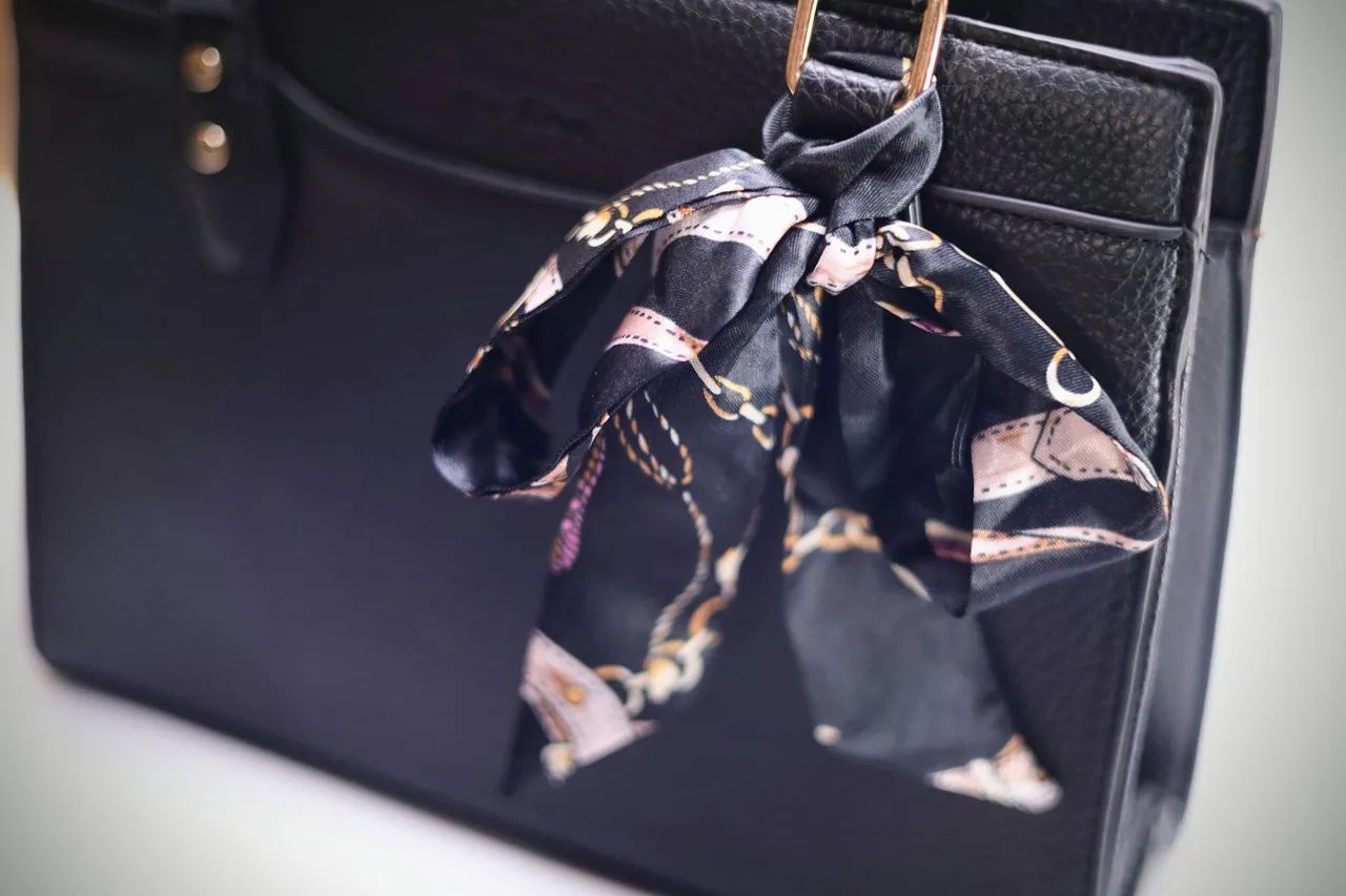 Bolsa de mão preta texturizada com alça trançada e lenço estampado. - Foto 2