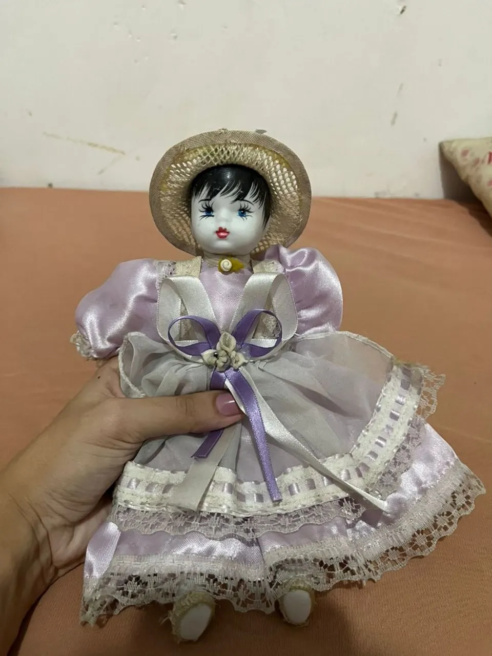 Linda boneca de porcelana com vestido lilás e chapéu